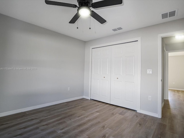 unfurnished bedroom featuring a closet, wood finished floors, visible vents, and baseboards