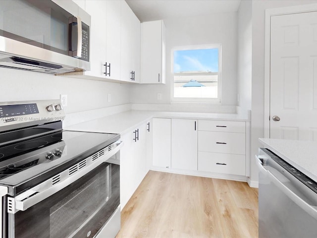 kitchen featuring appliances with stainless steel finishes, light countertops, light wood-style floors, and white cabinetry