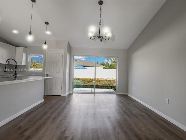 unfurnished dining area with dark wood-type flooring, baseboards, vaulted ceiling, and a sink