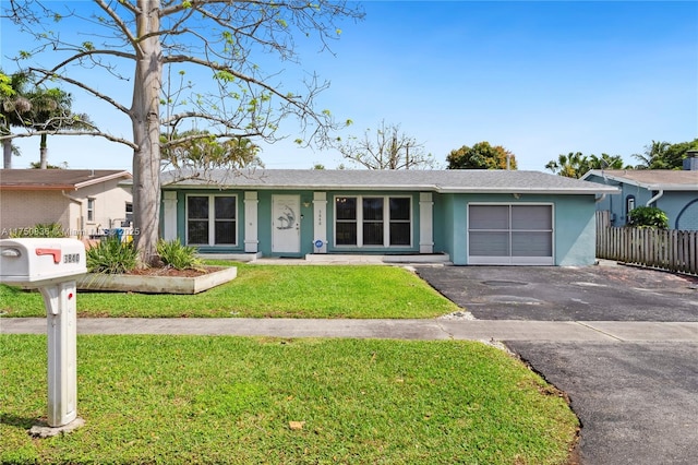 ranch-style house featuring aphalt driveway, a garage, fence, stucco siding, and a front yard