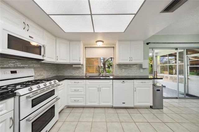 kitchen with white appliances, a sink, visible vents, and white cabinetry