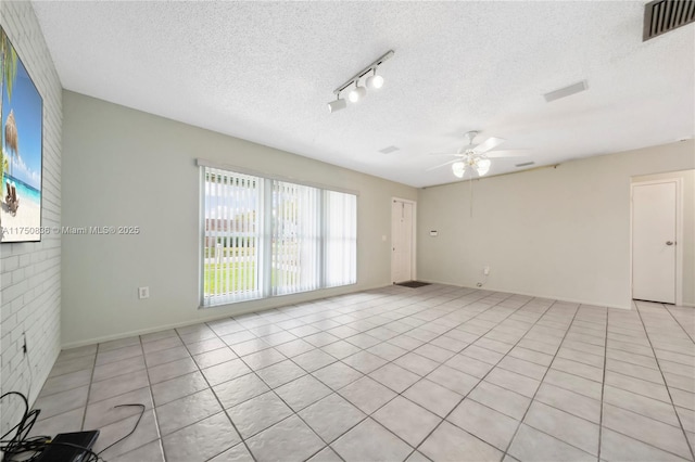 spare room featuring ceiling fan, visible vents, and a textured ceiling