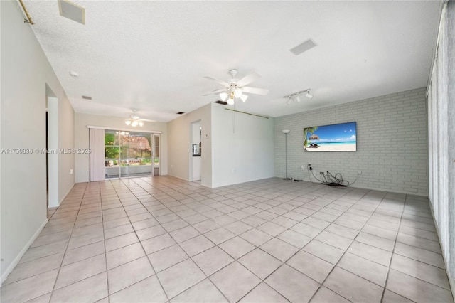 spare room featuring light tile patterned floors, a ceiling fan, brick wall, rail lighting, and a textured ceiling