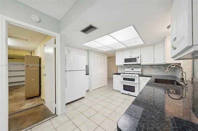 kitchen with white appliances, visible vents, white cabinets, and a sink