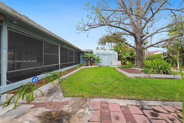 view of yard featuring an outbuilding, a sunroom, and a storage shed