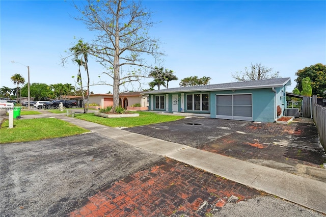 ranch-style house with stucco siding, fence, a garage, driveway, and a front lawn