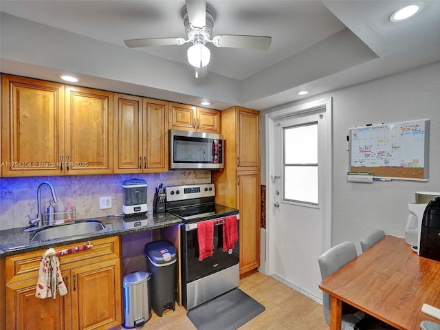 kitchen with decorative backsplash, appliances with stainless steel finishes, brown cabinets, light wood-style floors, and a sink