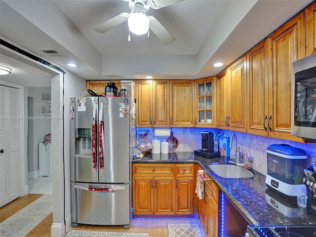 kitchen featuring stainless steel appliances, a sink, glass insert cabinets, and brown cabinets