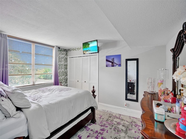 bedroom featuring a textured ceiling, a closet, and baseboards