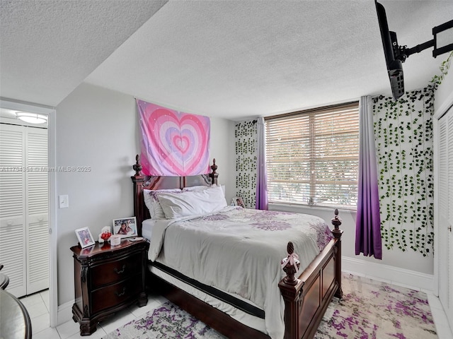 bedroom with a textured ceiling, light tile patterned flooring, and baseboards