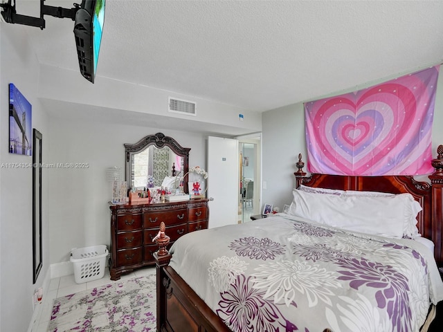 bedroom with a textured ceiling, light tile patterned floors, and visible vents