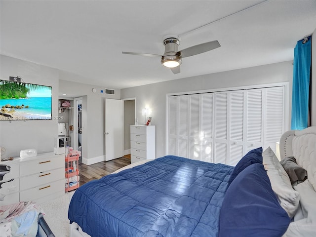 bedroom with baseboards, visible vents, ceiling fan, wood finished floors, and a closet