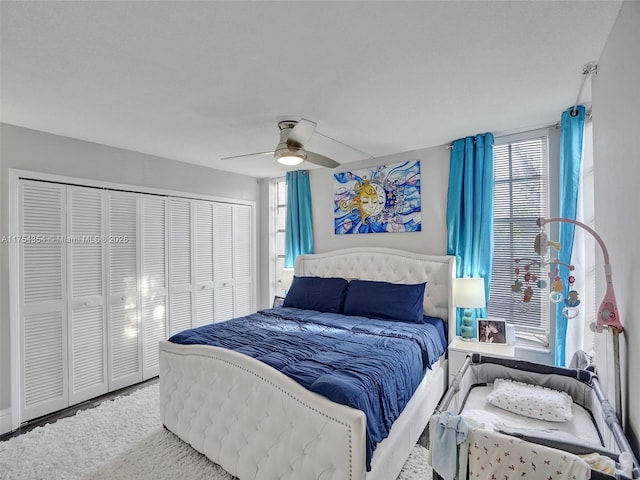 carpeted bedroom with a ceiling fan, a closet, and multiple windows