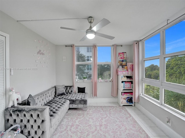 living area with a healthy amount of sunlight, ceiling fan, baseboards, and tile patterned floors