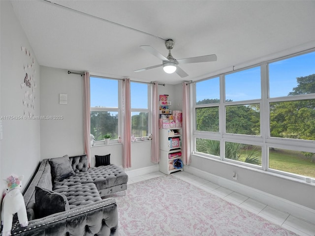 living area with light tile patterned floors, ceiling fan, and baseboards