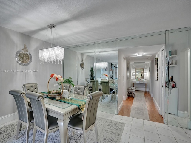 dining area featuring a chandelier, light tile patterned flooring, a textured ceiling, and baseboards