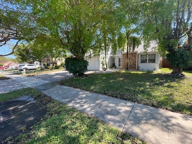 1350 S Fieldlark Ln, Homestead, FL 33035 - view of front of house with a front yard, stone siding, an attached garage, and concrete driveway