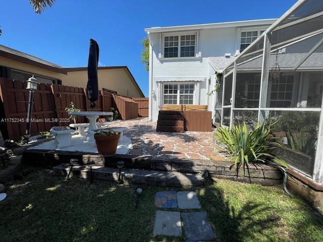 1350 S Fieldlark Ln, Homestead, FL 33035 - rear view of property featuring fence, a hot tub, stucco siding, a patio, and glass enclosure