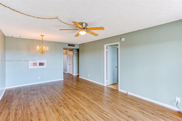 empty room with visible vents, baseboards, light wood-style flooring, a textured ceiling, and ceiling fan with notable chandelier