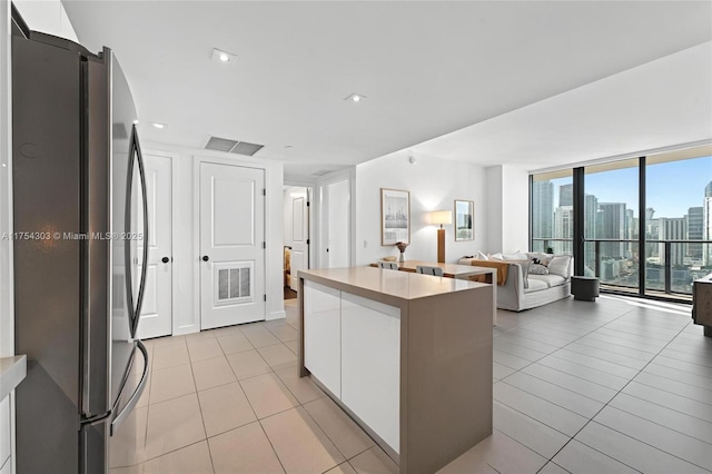 kitchen featuring visible vents, white cabinets, freestanding refrigerator, a center island, and a view of city