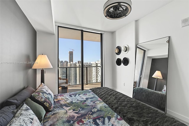 bedroom featuring expansive windows, a view of city, access to exterior, and baseboards