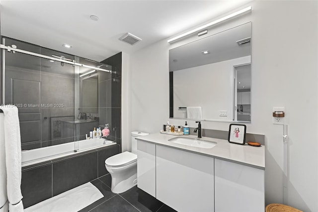 bathroom with visible vents, toilet, tiled shower / bath combo, vanity, and tile patterned flooring