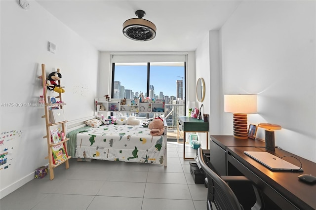 bedroom with baseboards, a wall of windows, tile patterned floors, and a city view