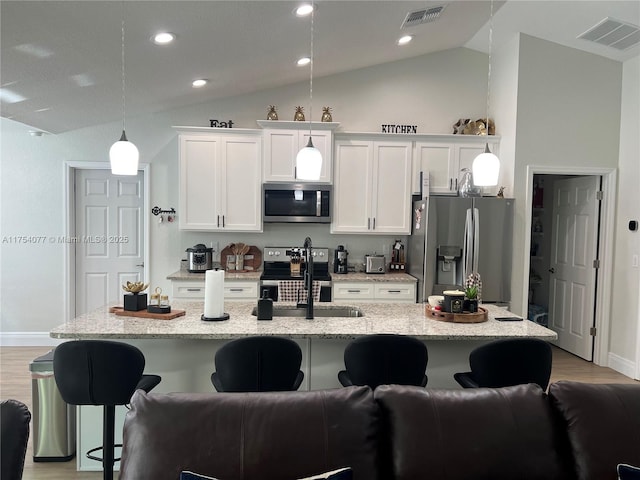 kitchen featuring a center island with sink, a breakfast bar area, visible vents, appliances with stainless steel finishes, and white cabinets