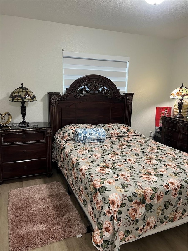 bedroom with a textured ceiling and wood finished floors