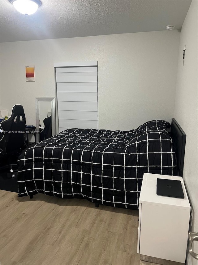 bedroom featuring a textured ceiling and wood finished floors