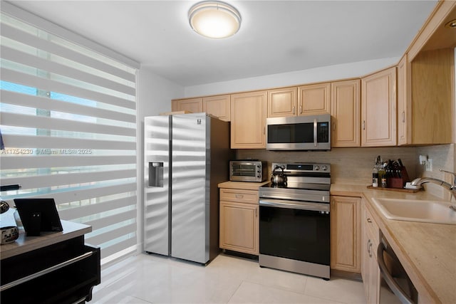 kitchen featuring light countertops, backsplash, appliances with stainless steel finishes, light brown cabinets, and a sink