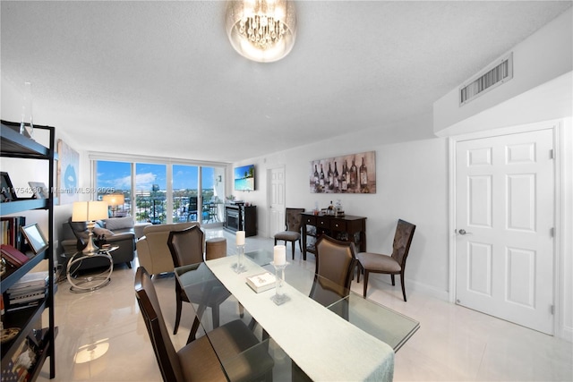 dining area with light tile patterned floors, visible vents, a wall of windows, a textured ceiling, and a chandelier