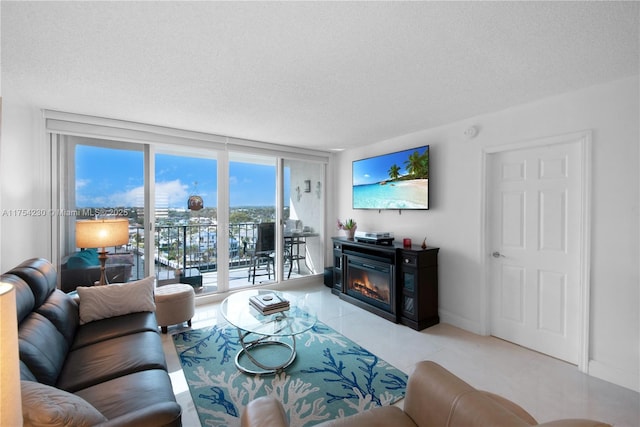 living room featuring a textured ceiling, a wall of windows, a glass covered fireplace, and baseboards