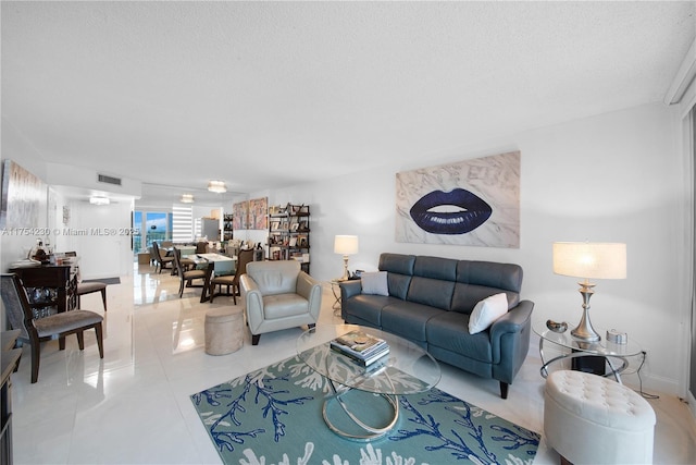 tiled living room featuring a textured ceiling and visible vents