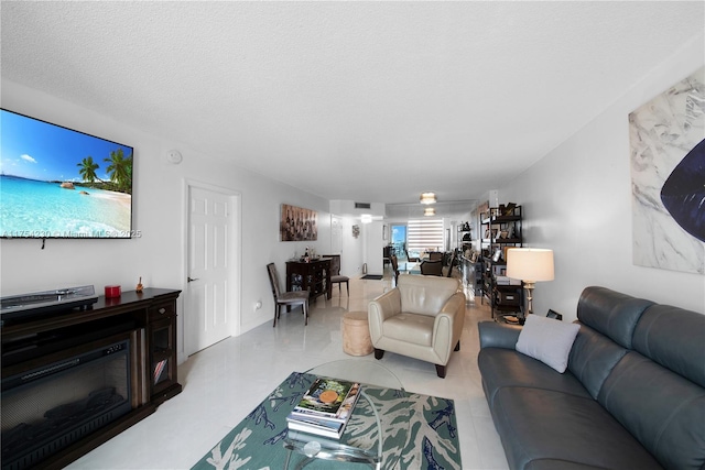 living area featuring a textured ceiling, a glass covered fireplace, and visible vents