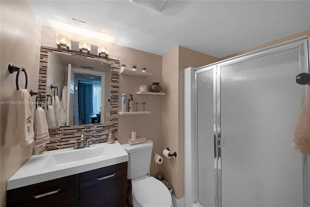 bathroom featuring toilet, a shower stall, decorative backsplash, and vanity