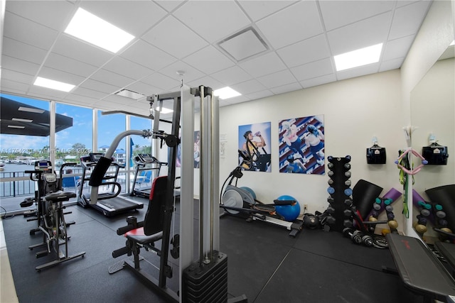 exercise room featuring a paneled ceiling and floor to ceiling windows