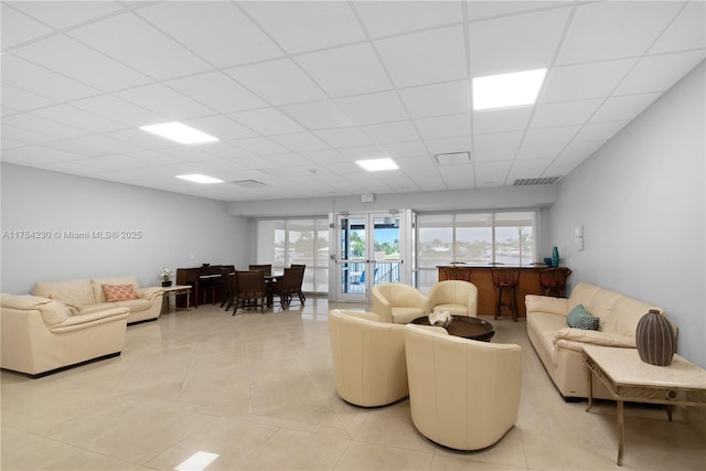 living area featuring a drop ceiling, visible vents, and light tile patterned floors