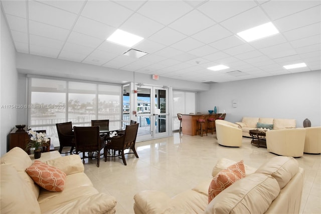 tiled living area with a paneled ceiling, french doors, and visible vents