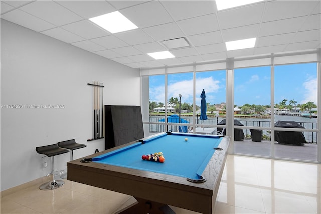 game room featuring a healthy amount of sunlight, a drop ceiling, and floor to ceiling windows