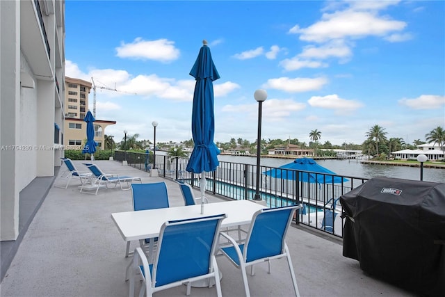 view of patio with a water view, a grill, and outdoor dining area