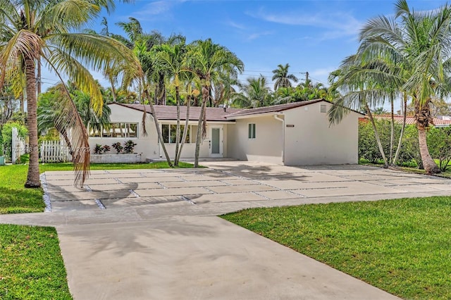 view of front of property with a front yard, fence, and stucco siding