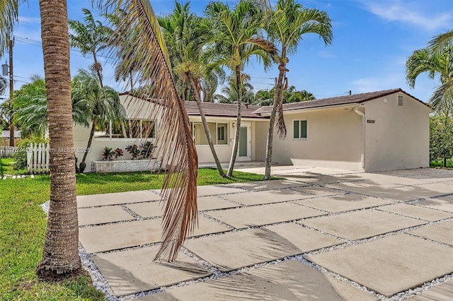 rear view of property featuring driveway, fence, and stucco siding