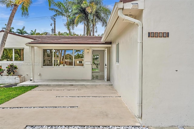 entrance to property with a patio and stucco siding