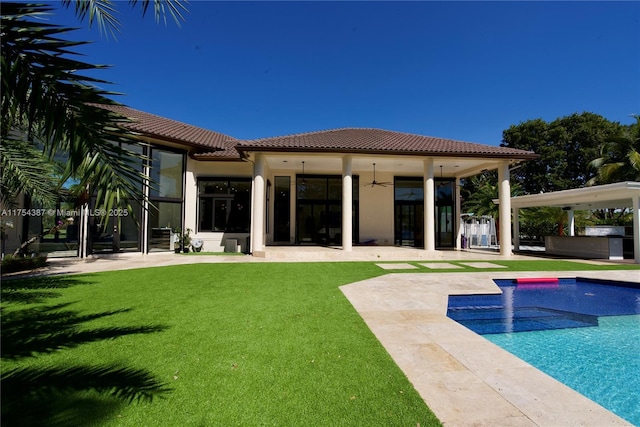 rear view of property featuring a patio area, a tile roof, a lawn, and ceiling fan