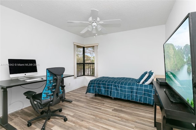 bedroom with a textured ceiling, wood finished floors, a ceiling fan, and baseboards