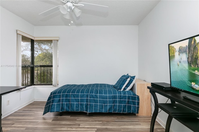 bedroom with ceiling fan, a textured ceiling, and wood finished floors