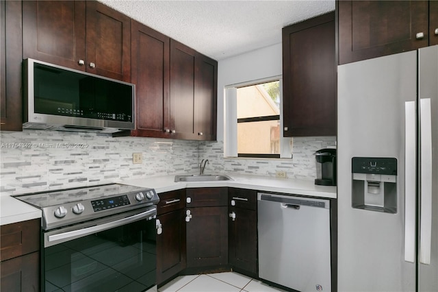 kitchen featuring appliances with stainless steel finishes, light countertops, a sink, and backsplash