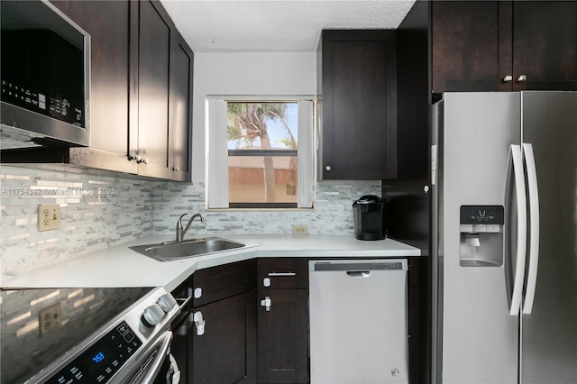 kitchen with light countertops, backsplash, appliances with stainless steel finishes, a sink, and dark brown cabinets