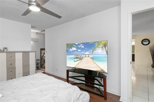 bedroom with a ceiling fan, baseboards, a textured ceiling, and wood finished floors